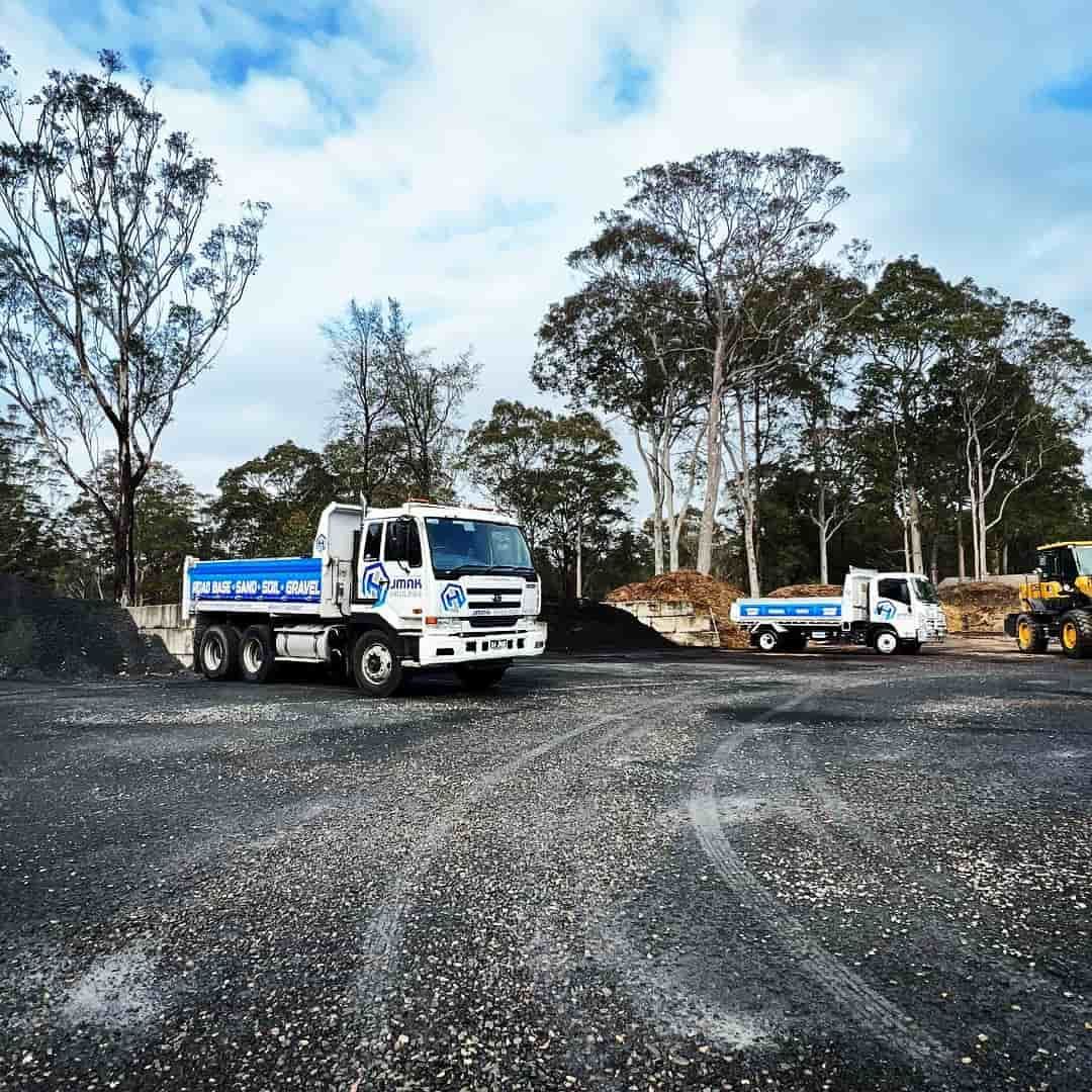 Two Dump Trucks Are Parked In A Gravel Lot With Trees — JMAK Haulage & Landscapes Supplies In Berry, NSW