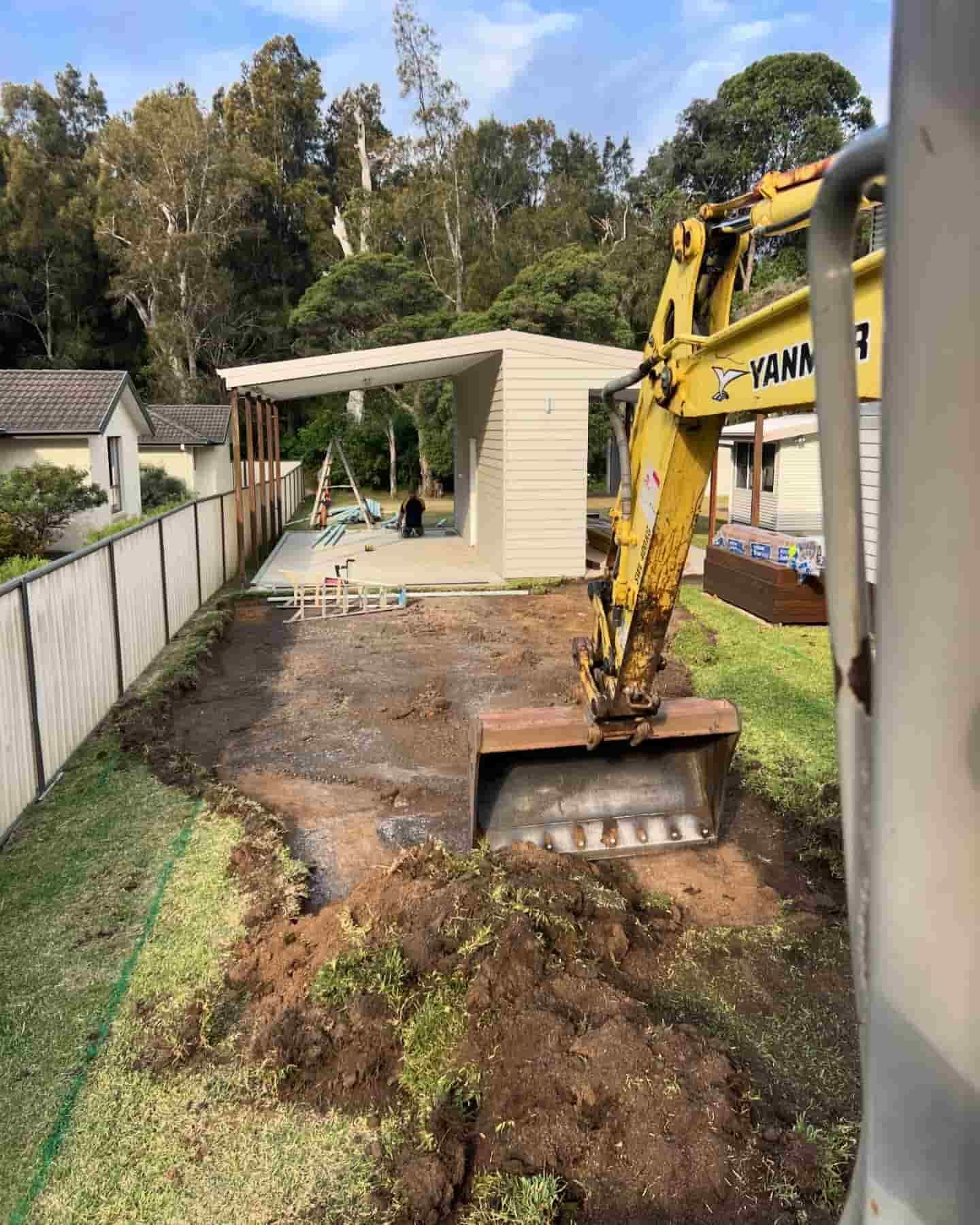 A Yellow Excavator Is Digging A Hole In A Yard — JMAK Haulage & Landscapes Supplies In Ulladulla, NSW