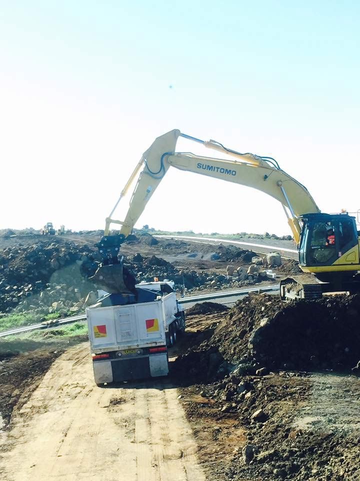 An Excavator Is Loading Dirt Into A Truck On A Dirt Road — JMAK Haulage & Landscapes Supplies In Falls Creek, NSW