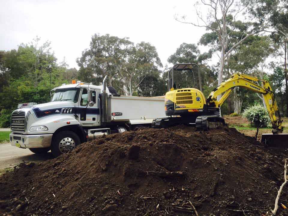 A Dump Truck Is Parked Next To A Yellow Excavator — JMAK Haulage & Landscapes Supplies In Vincentia, NSW