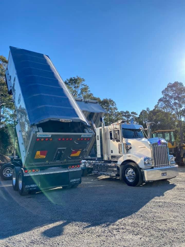 A Dump Truck With Its Bed Up Is Parked In A Gravel Lot — JMAK Haulage & Landscapes Supplies In Vincentia, NSW