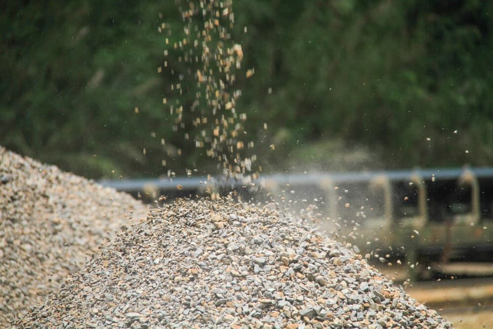 A Pile Of Gravel Is Being Poured Onto A Conveyor Belt — JMAK Haulage & Landscapes Supplies In Falls Creek, NSW