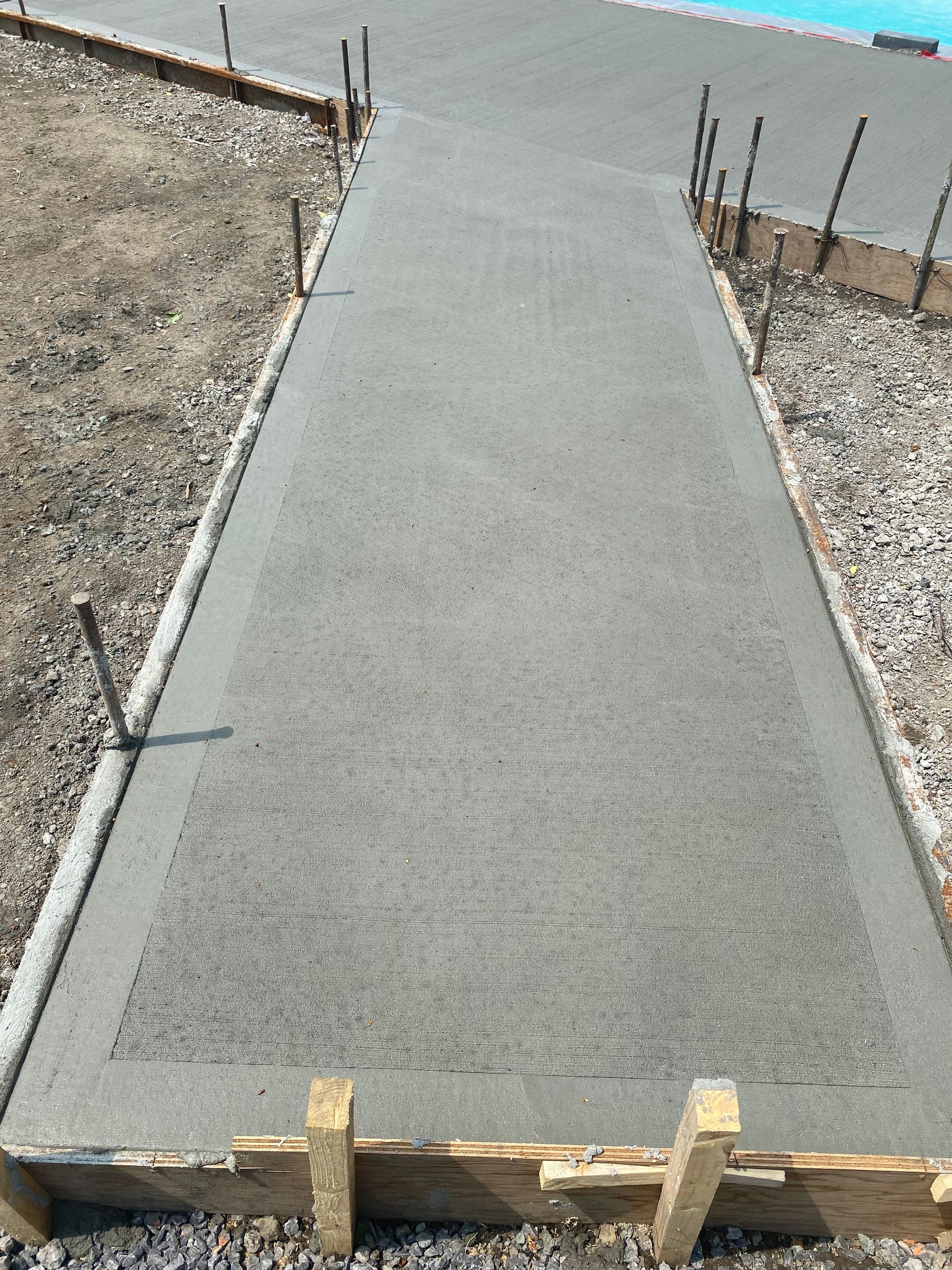 Une passerelle en béton est en cours de construction à côté d'une piscine.