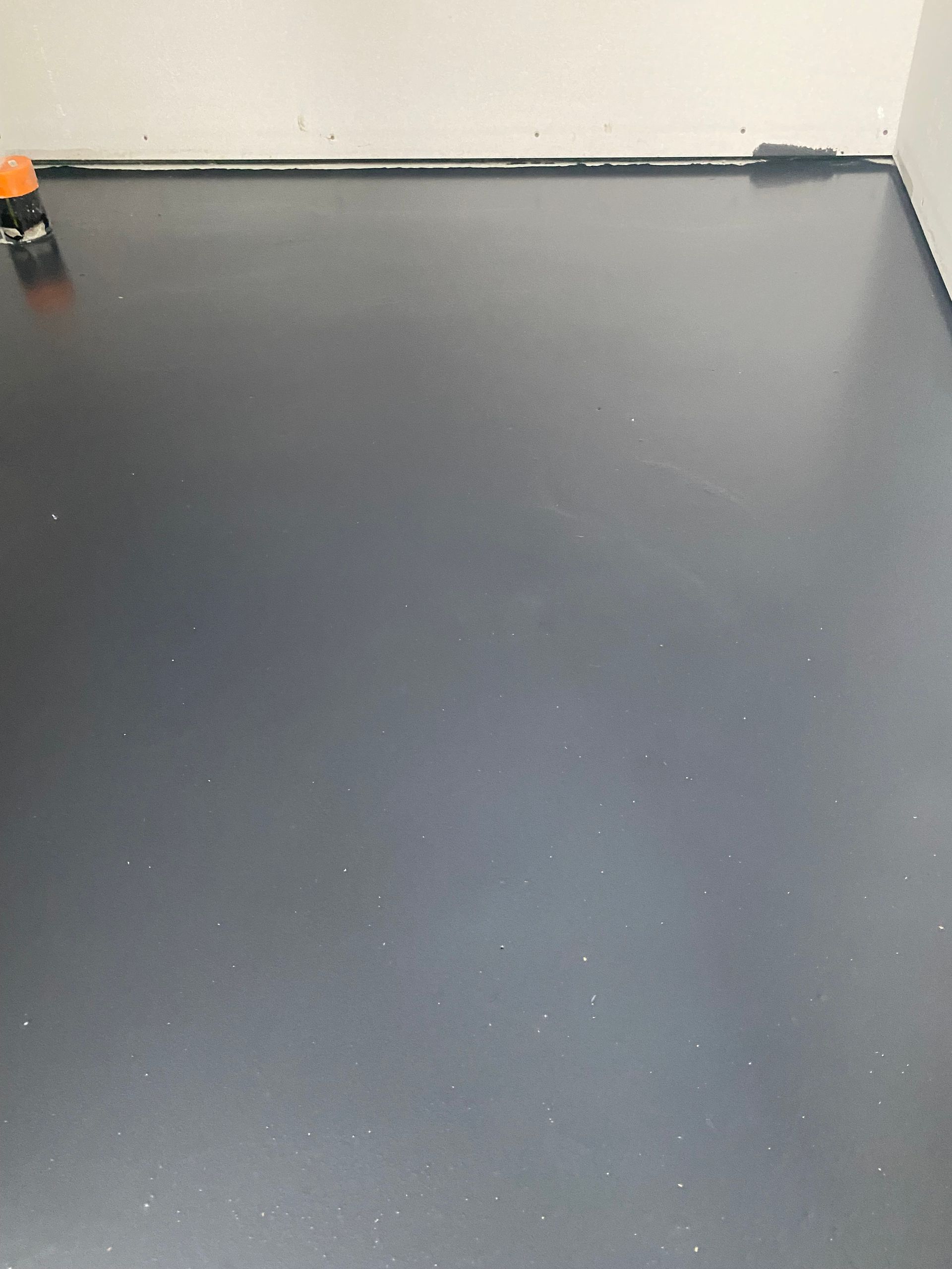 Un sol noir avec un mur blanc en arrière-plan.