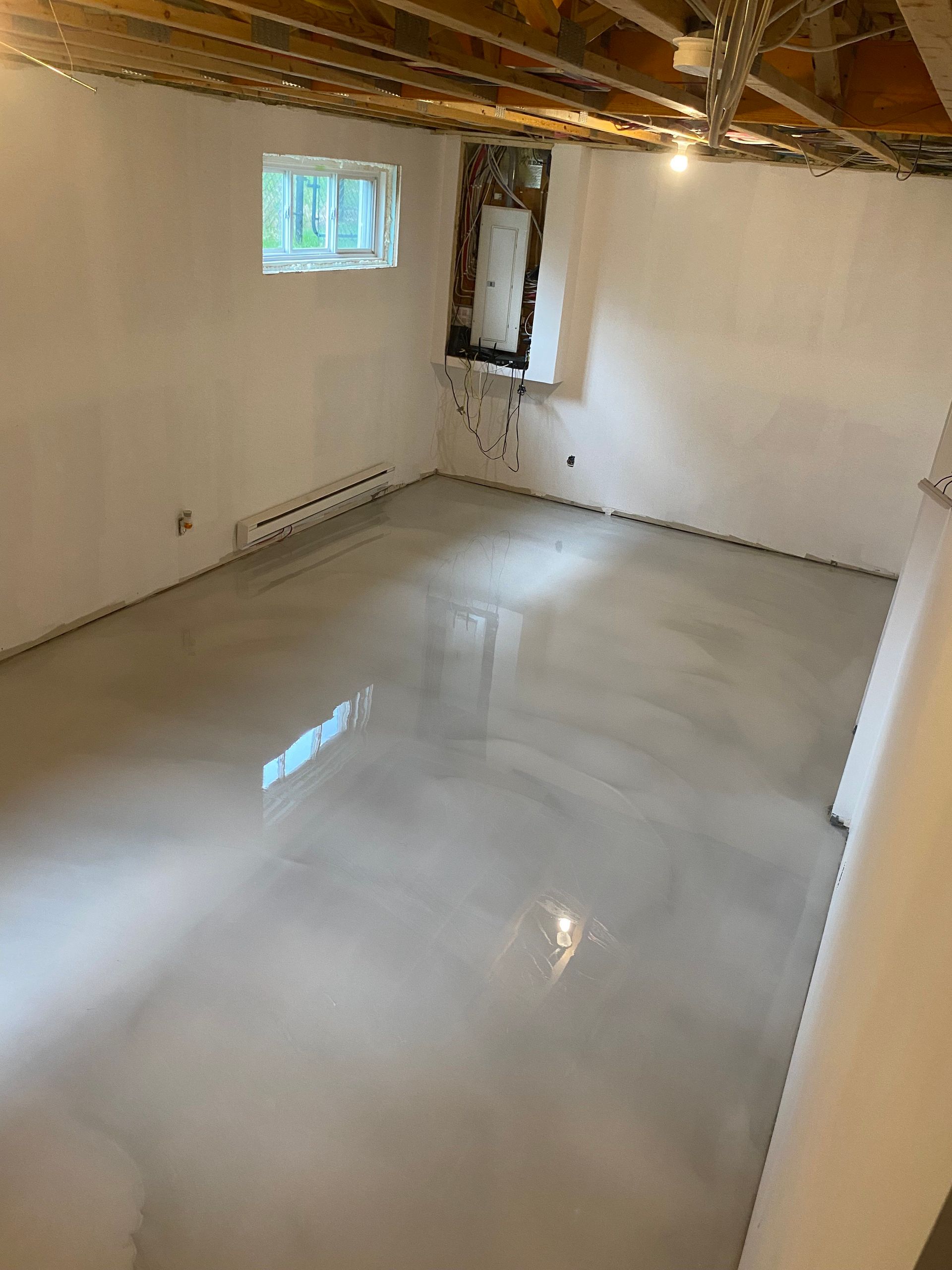 Une pièce avec un sol en béton brillant et des murs blancs.