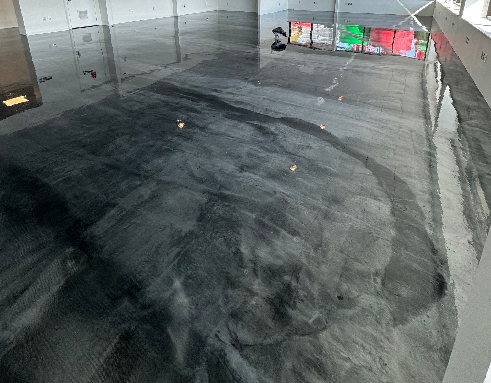 Un sol métallique noir dans une pièce avec le reflet d'un vitrail.