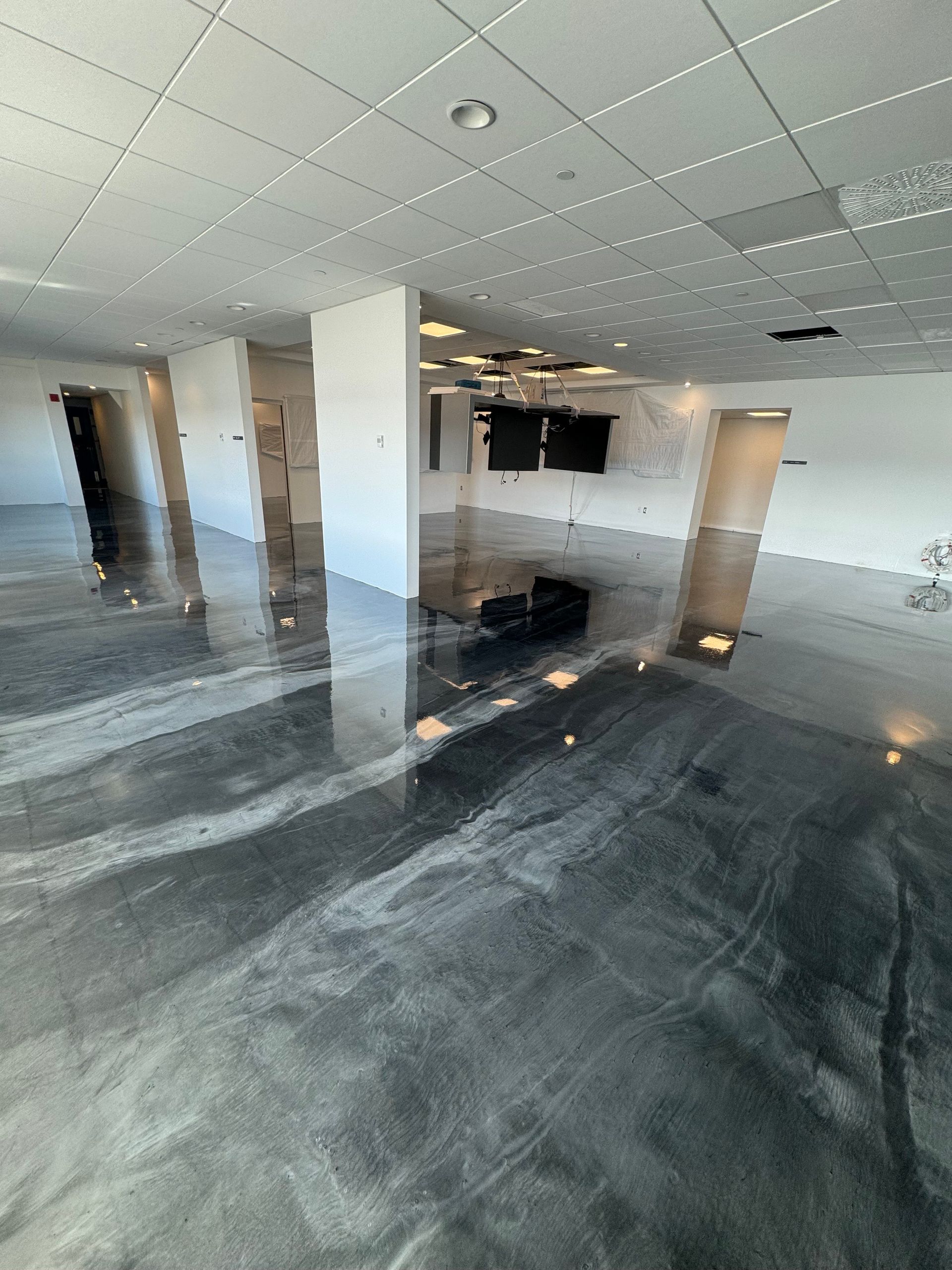 Une grande pièce avec un sol métallique brillant et des murs blancs.