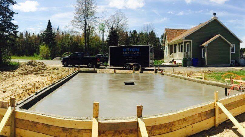 Une fondation en béton est en train d'être construite devant une maison.