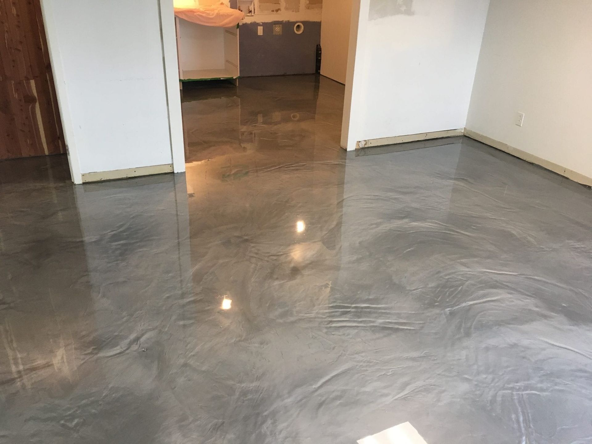 Une pièce avec un sol métallique brillant et des murs blancs.