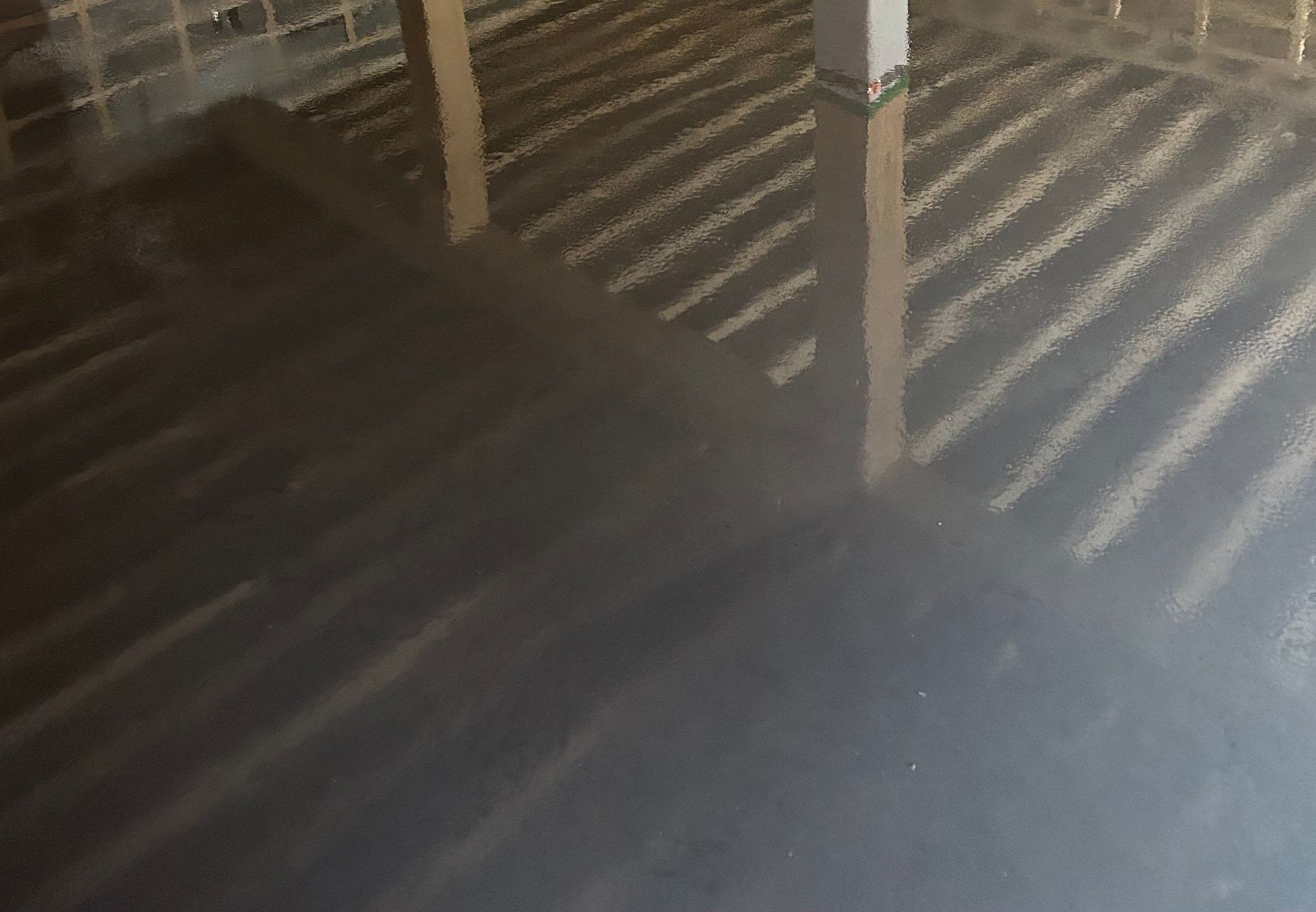 Vue aérienne d'un grenier avec charpente et isolation, éclairé par la lumière du soleil, tons sombres.