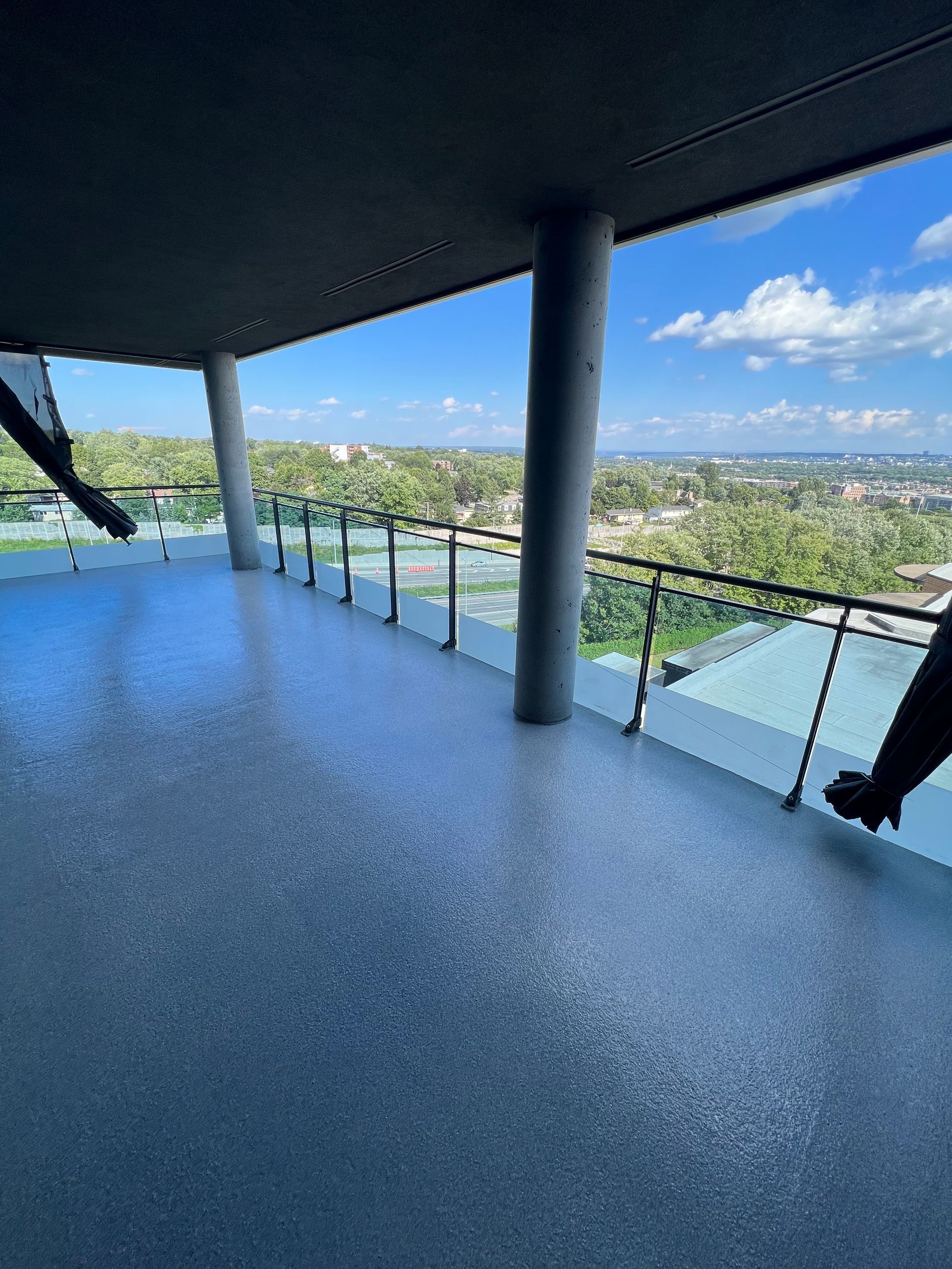 Un balcon avec vue sur une ville et des arbres.