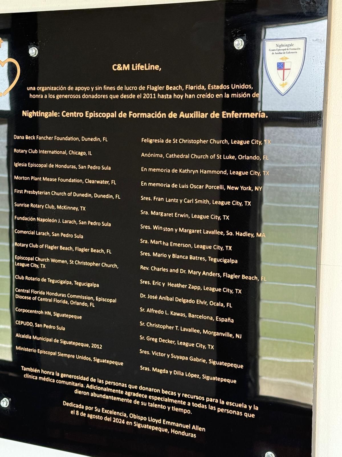 Black plaque with names in Spanish, dedication to a nursing auxiliary school in the Dominican Republic.