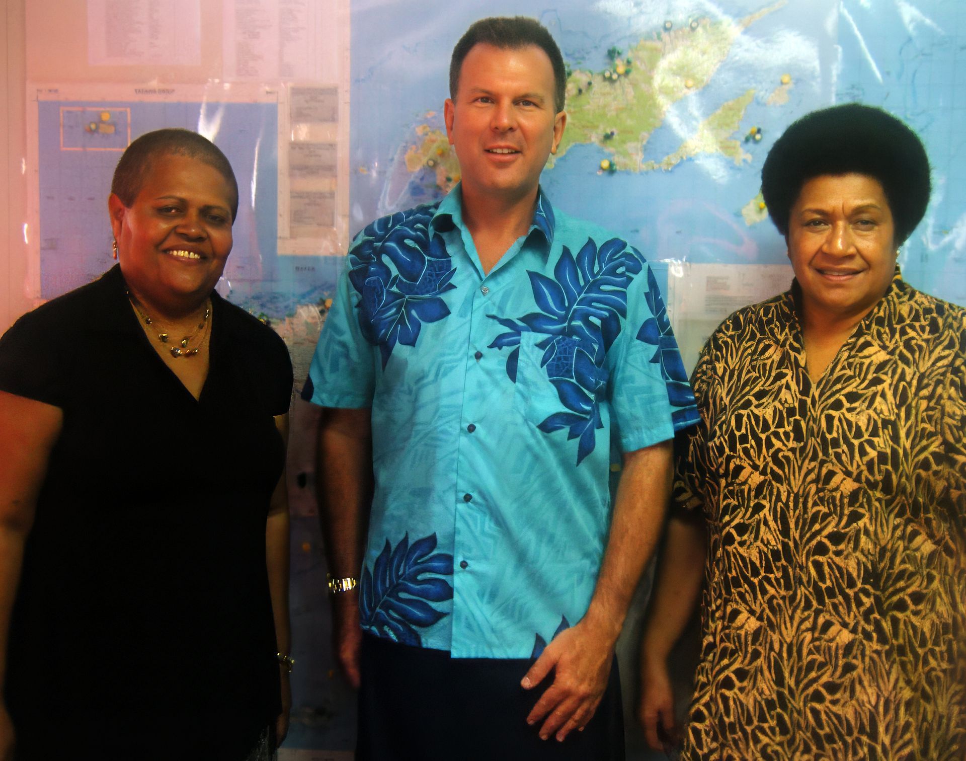 three people standing in front of a map of the world