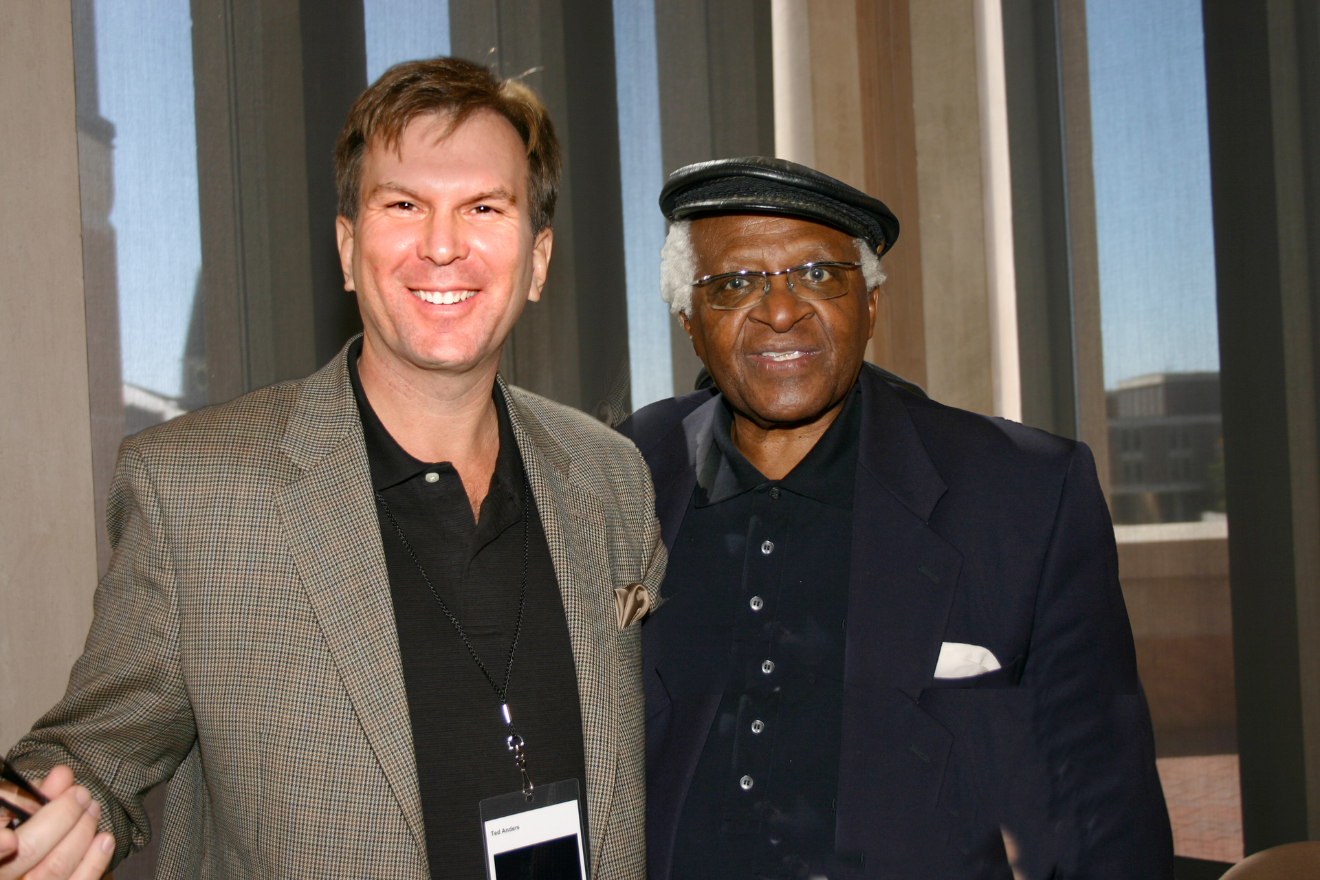 two men posing for a picture in front of a window