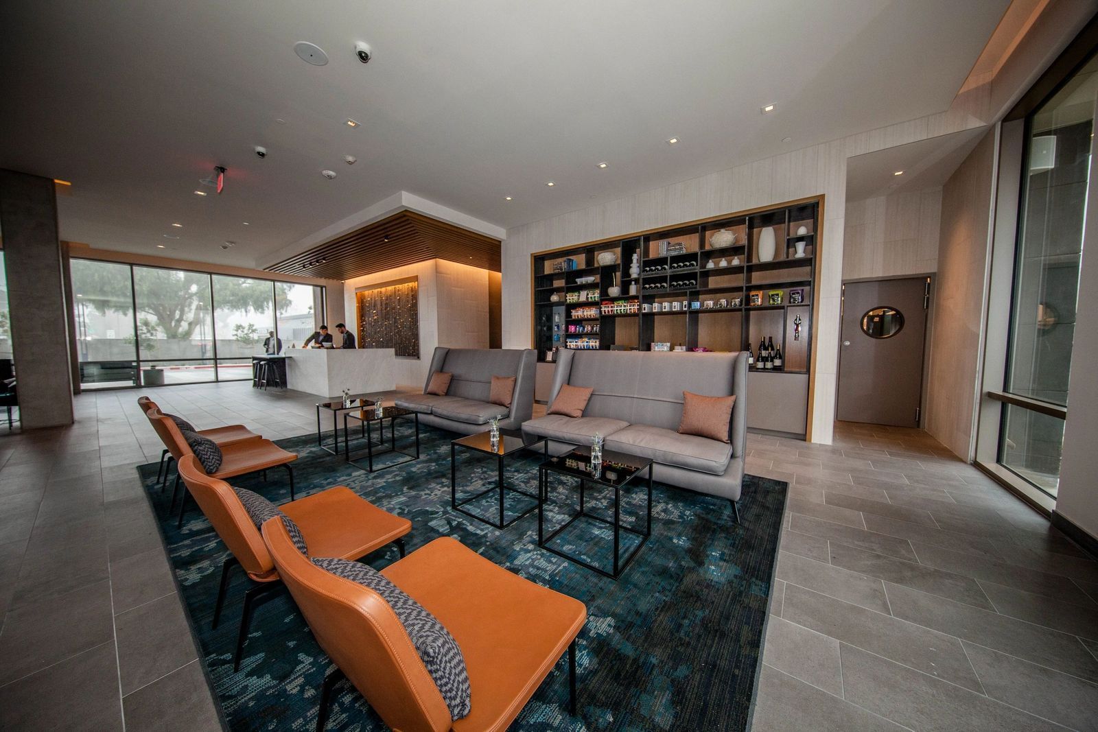 Modern hotel lobby with seating, a reception desk, and a built-in shelf display.
