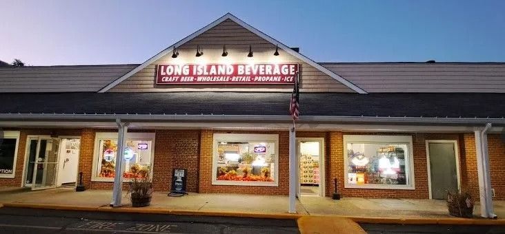 Long Island Beverage store with a lit sign above the entrance, at dusk.