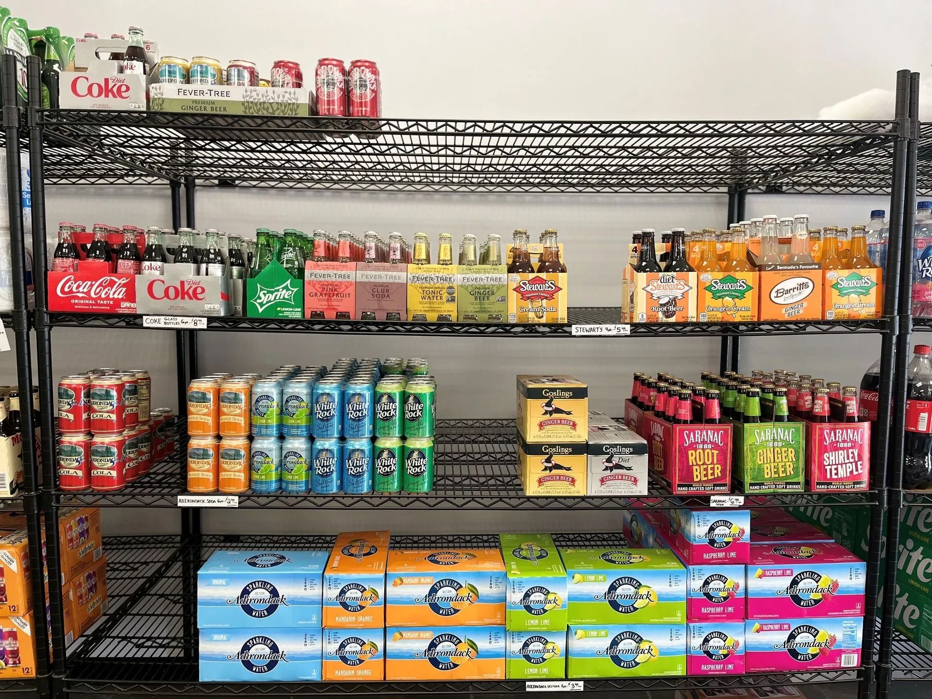 Shelves stocked with various soda brands in cans and bottles, organized in a retail setting.
