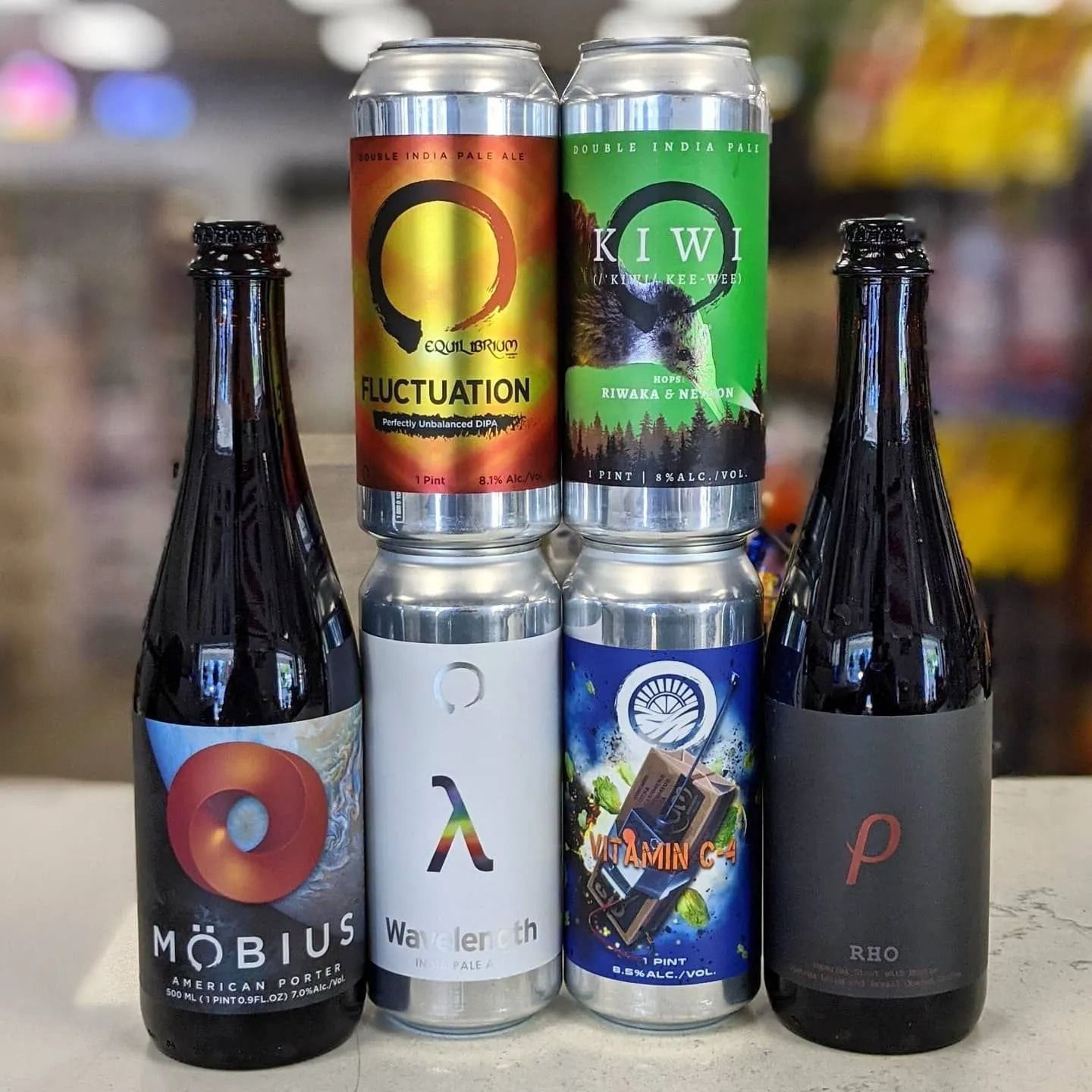 Assortment of craft beer: six cans and two dark glass bottles with colorful labels in a store.