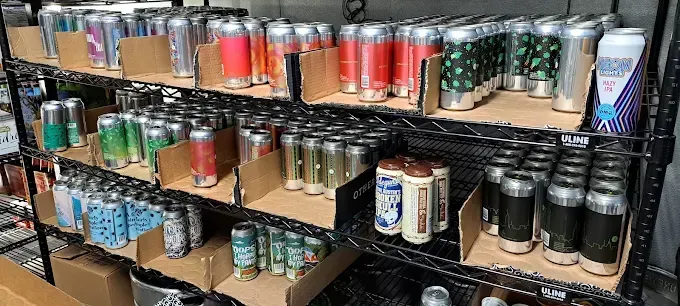 Shelves stocked with cans of beverages, arranged in rows behind cardboard dividers.
