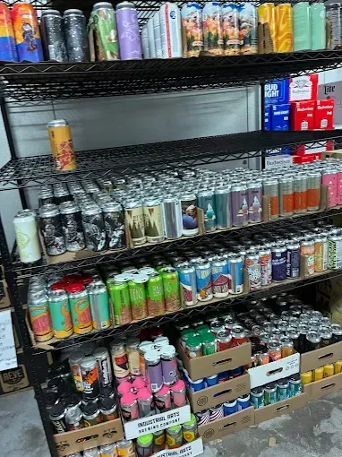 Shelves stocked with various colorful beer cans. A shop interior is visible.