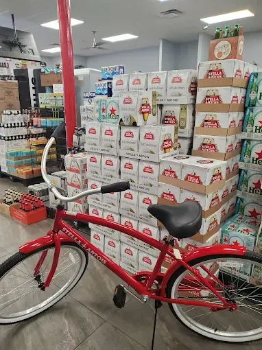 Red bicycle parked in front of stacked beer cases inside a store.