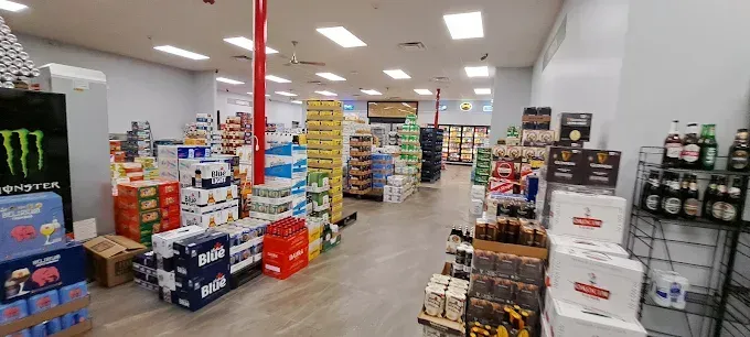 Interior of a beer and beverage store with aisles of stacked products. Red support beams run through the store.