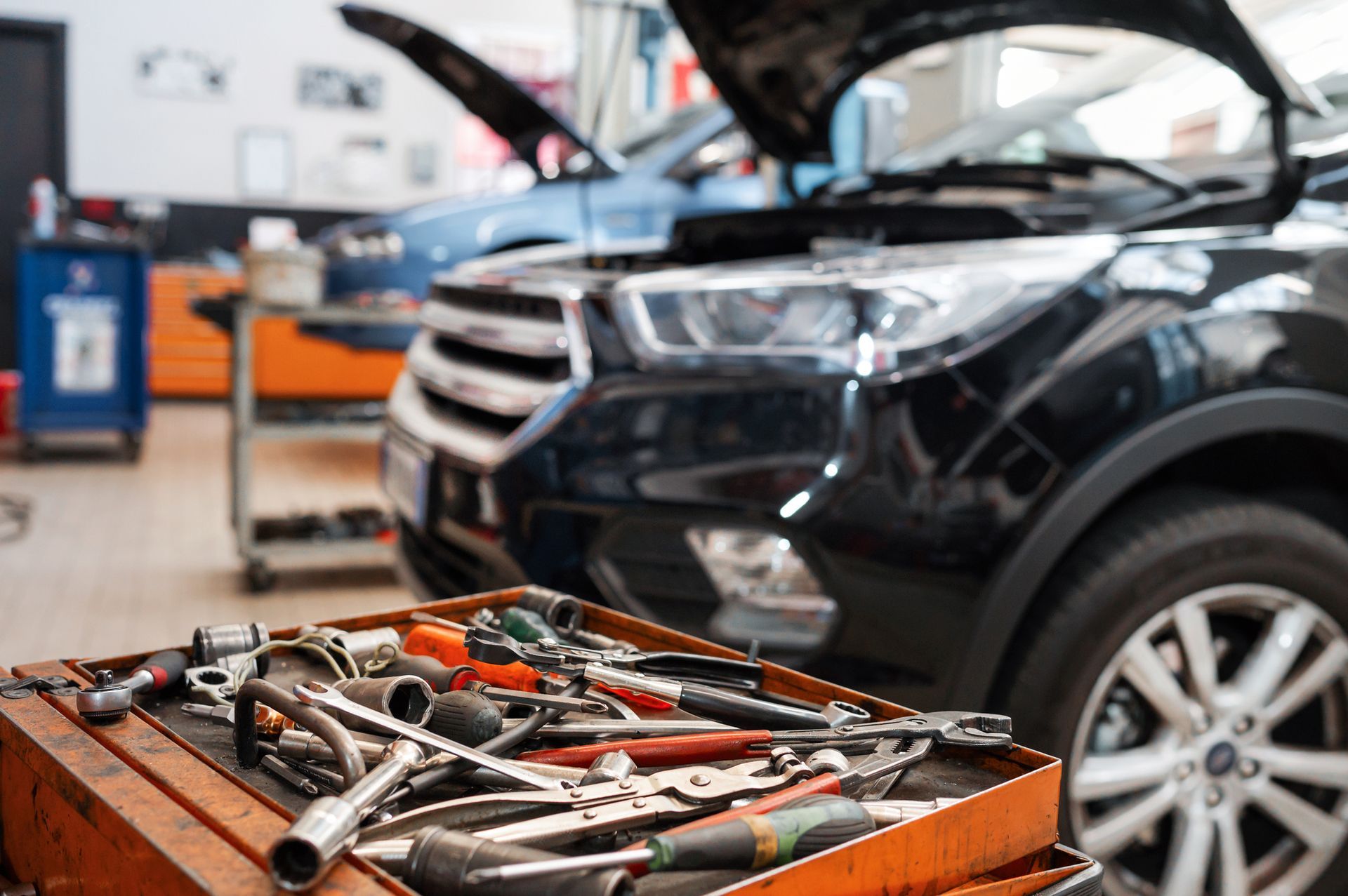 A box of tools is sitting in front of a car in a garage.