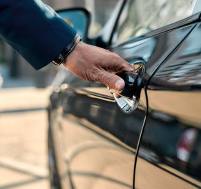 A person is opening the door of a car with a key.
