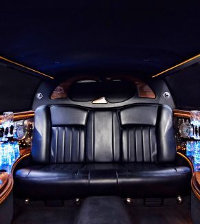 The back seat of a limousine with bottles of water on the side