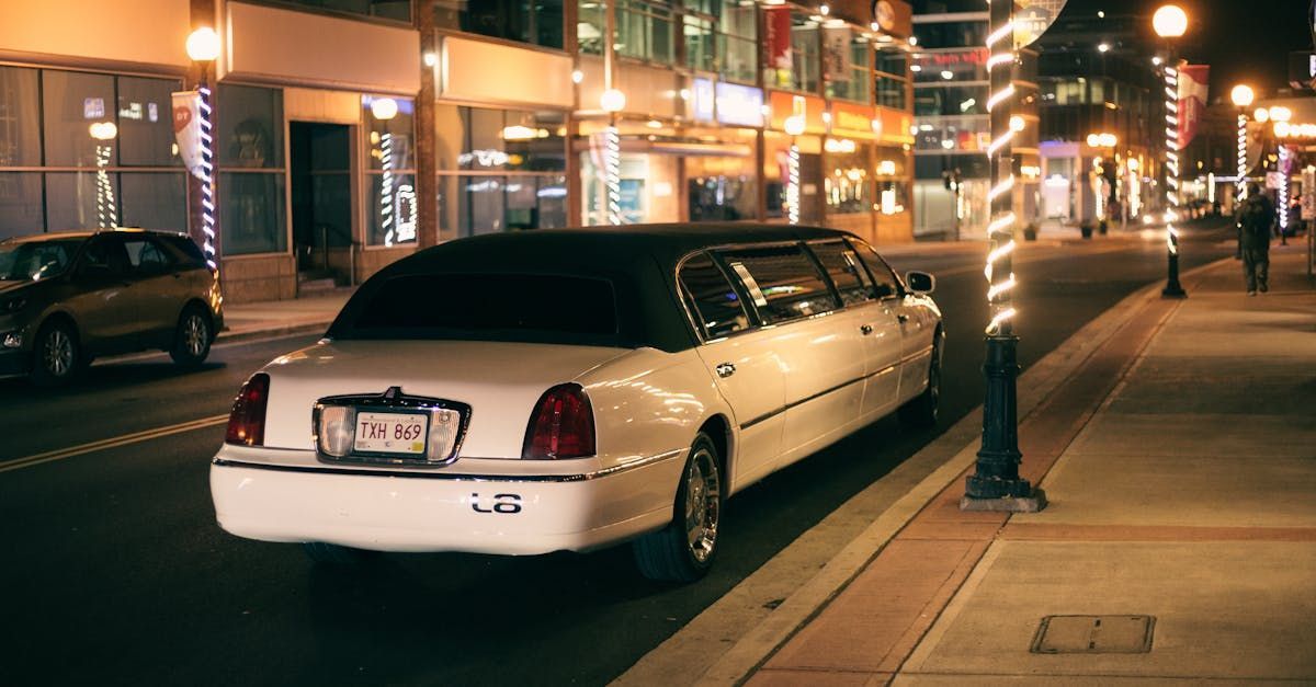 A white limousine is parked on the side of a city street at night.