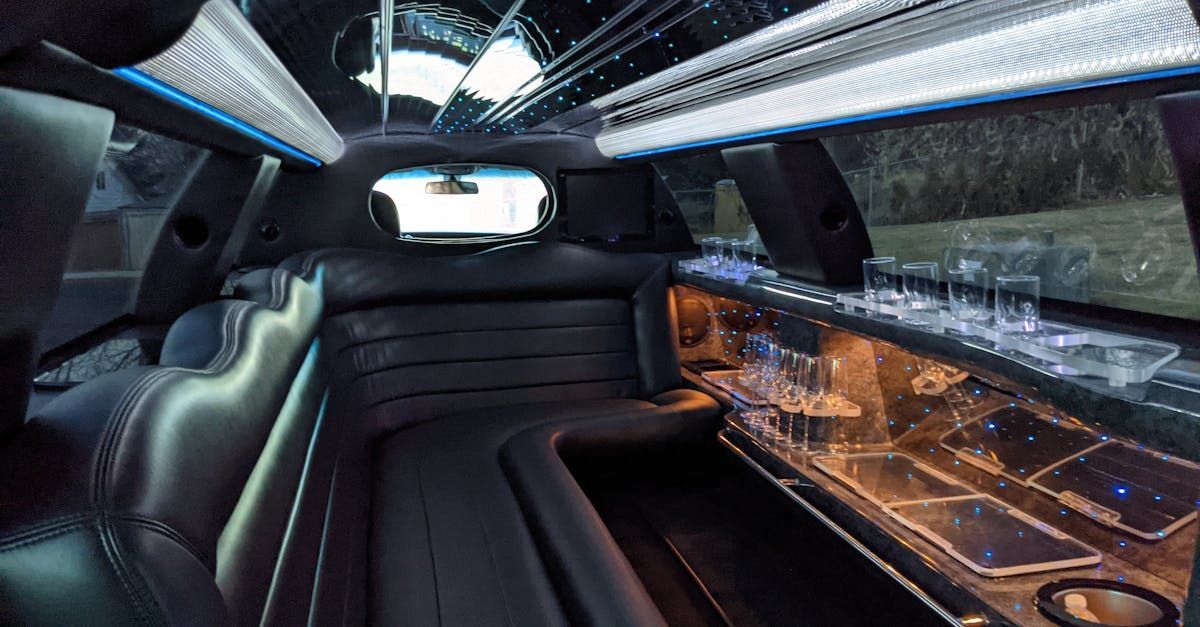 The inside of a limousine with a long couch and a bar.