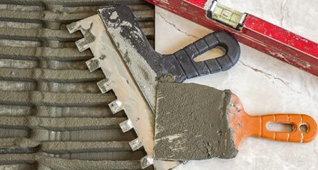 A Spatula and a Level Are Sitting on Top of a Tile Floor — Northern Tile Gallery in Winnellie, NT