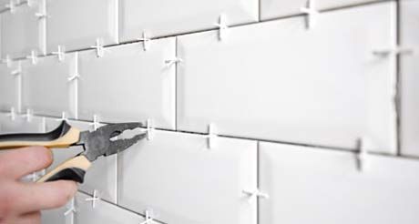 A Person is Using Pliers to Install Tiles on a Wall — Northern Tile Gallery in Winnellie, NT