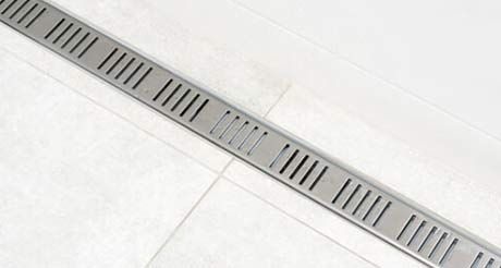 A Stainless Steel Shower Drain is Sitting on a Tiled Floor — Northern Tile Gallery in Winnellie, NT
