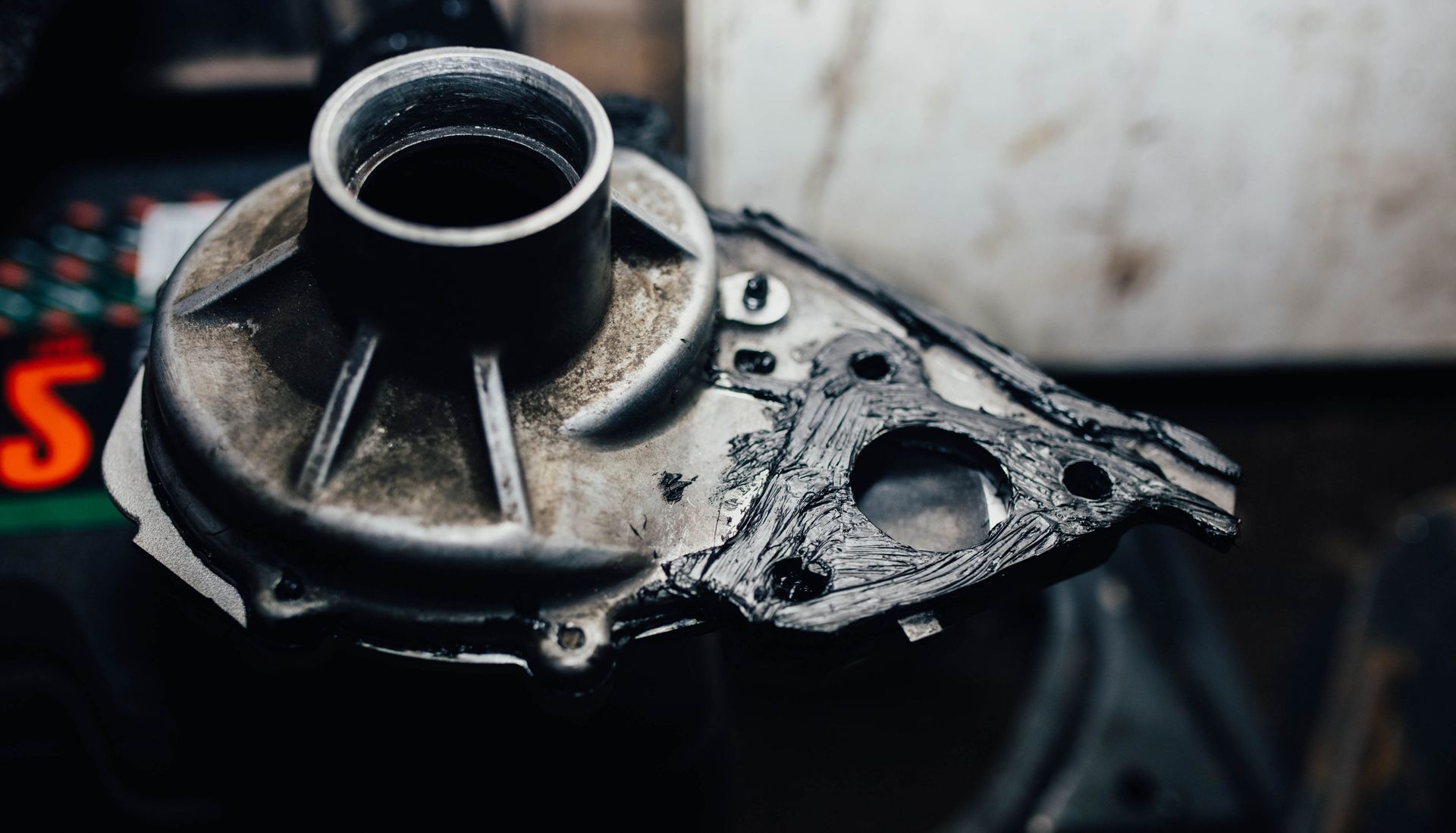 Close-up of a damaged black metal mechanical part with bolts on a dark surface Close-up of a damaged black metal mechanical part with bolts on a dark surface