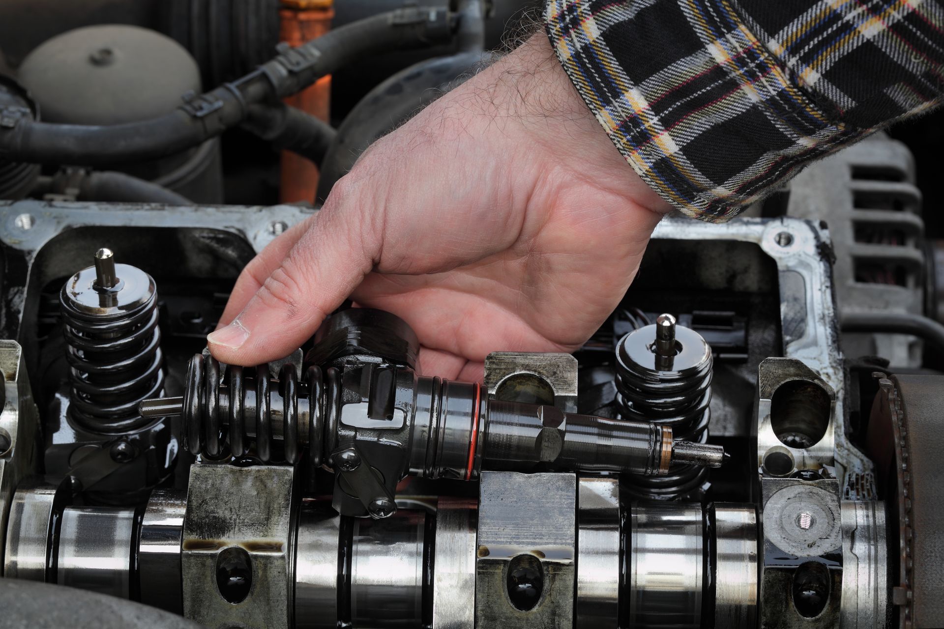Hand inspecting a car engine’s camshaft and valve springs under the hood Hand inspecting a car engine’s camshaft and valve springs under the hood