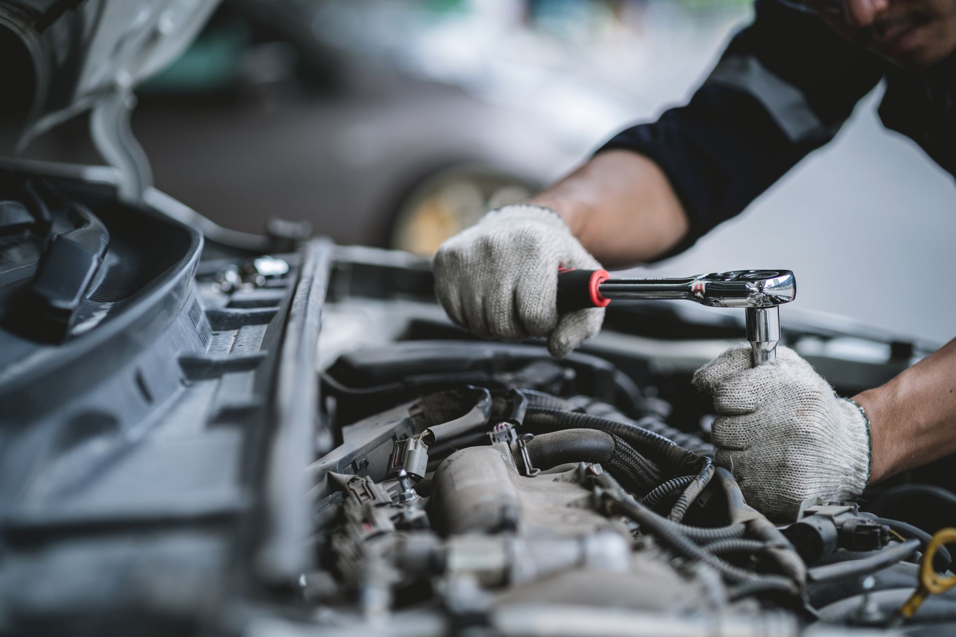 Mechanic using a ratchet wrench to repair a car engine in a garage Mechanic using a ratchet wrench to repair a car engine in a garage