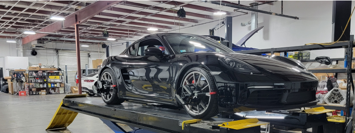 A black sports car is sitting on a lift in a garage | Adler Rennsport
