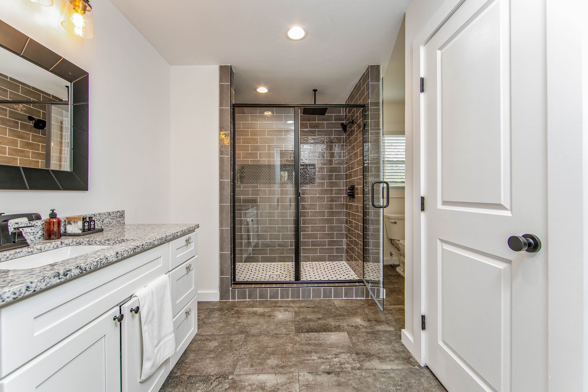 A bathroom with a walk in shower , sink and mirror.