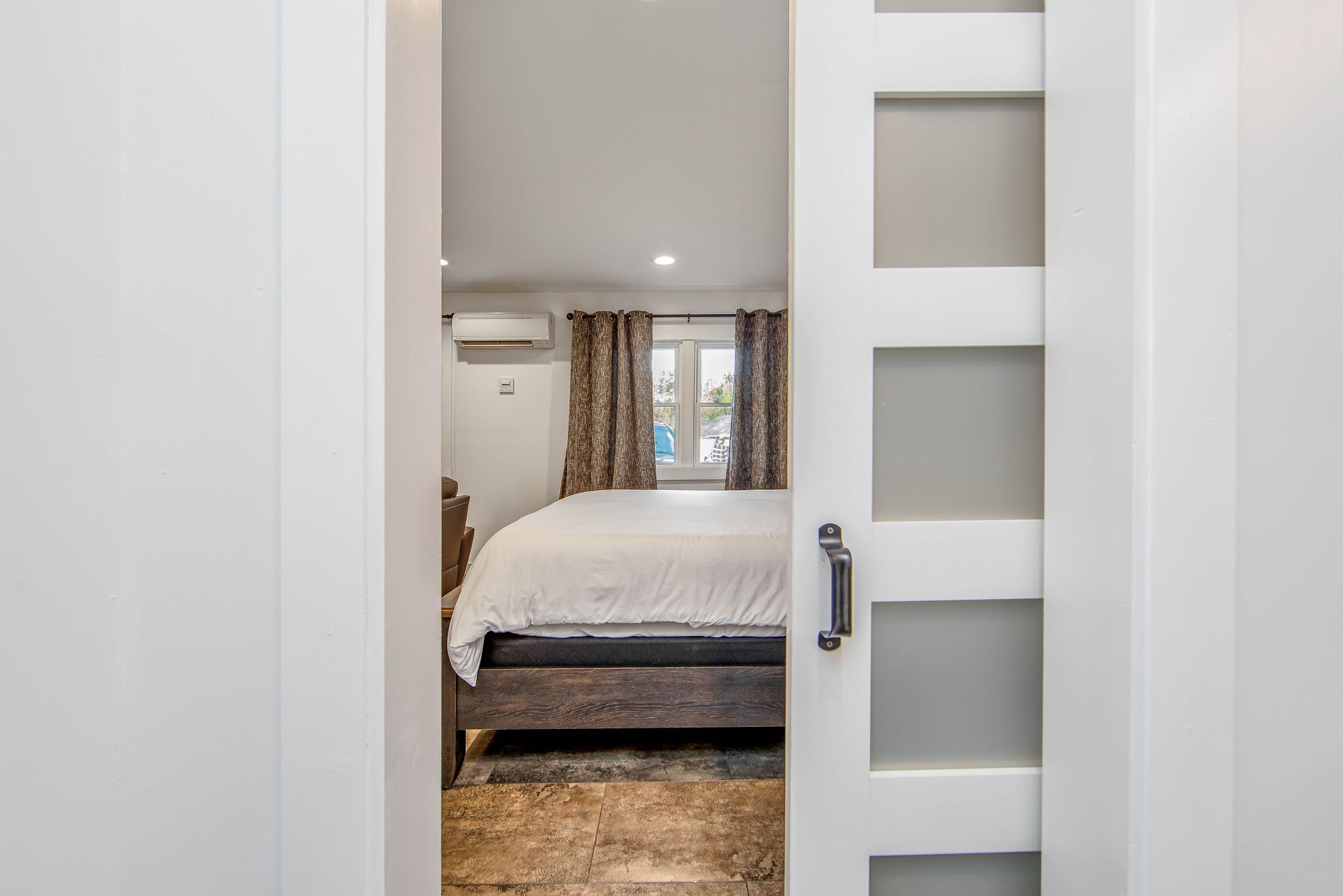 A bedroom with a sliding glass door leading to a bed.