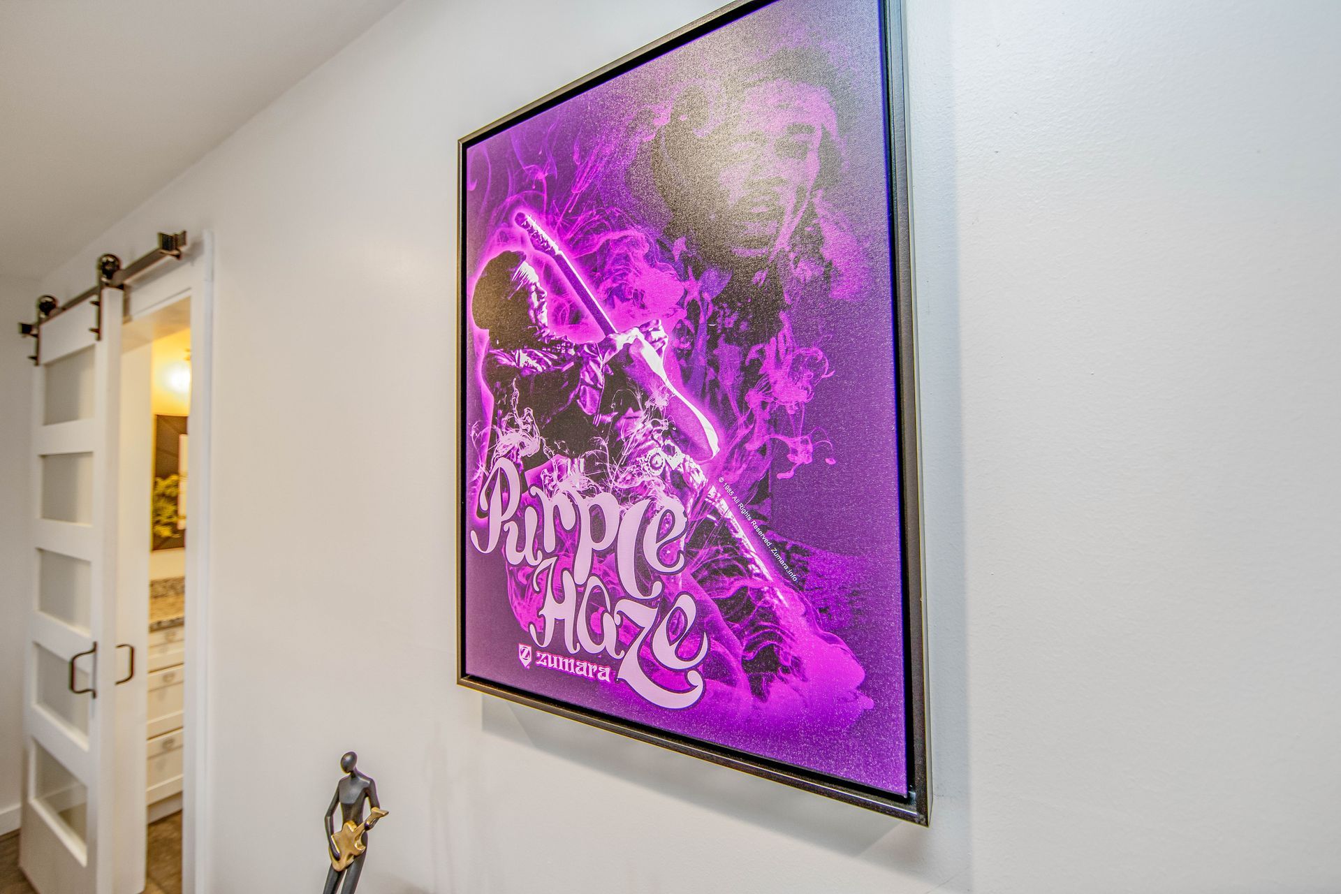 A purple painting is hanging on a white wall.