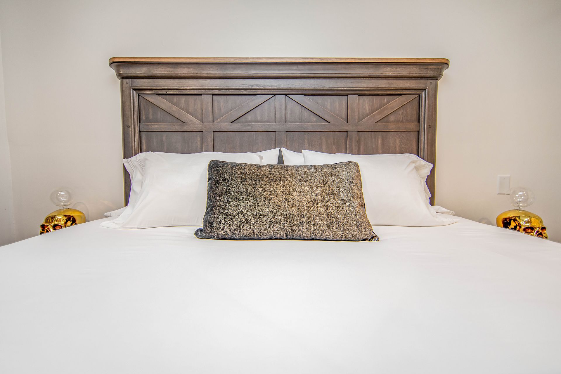 A bed with a wooden headboard and pillows in a bedroom.