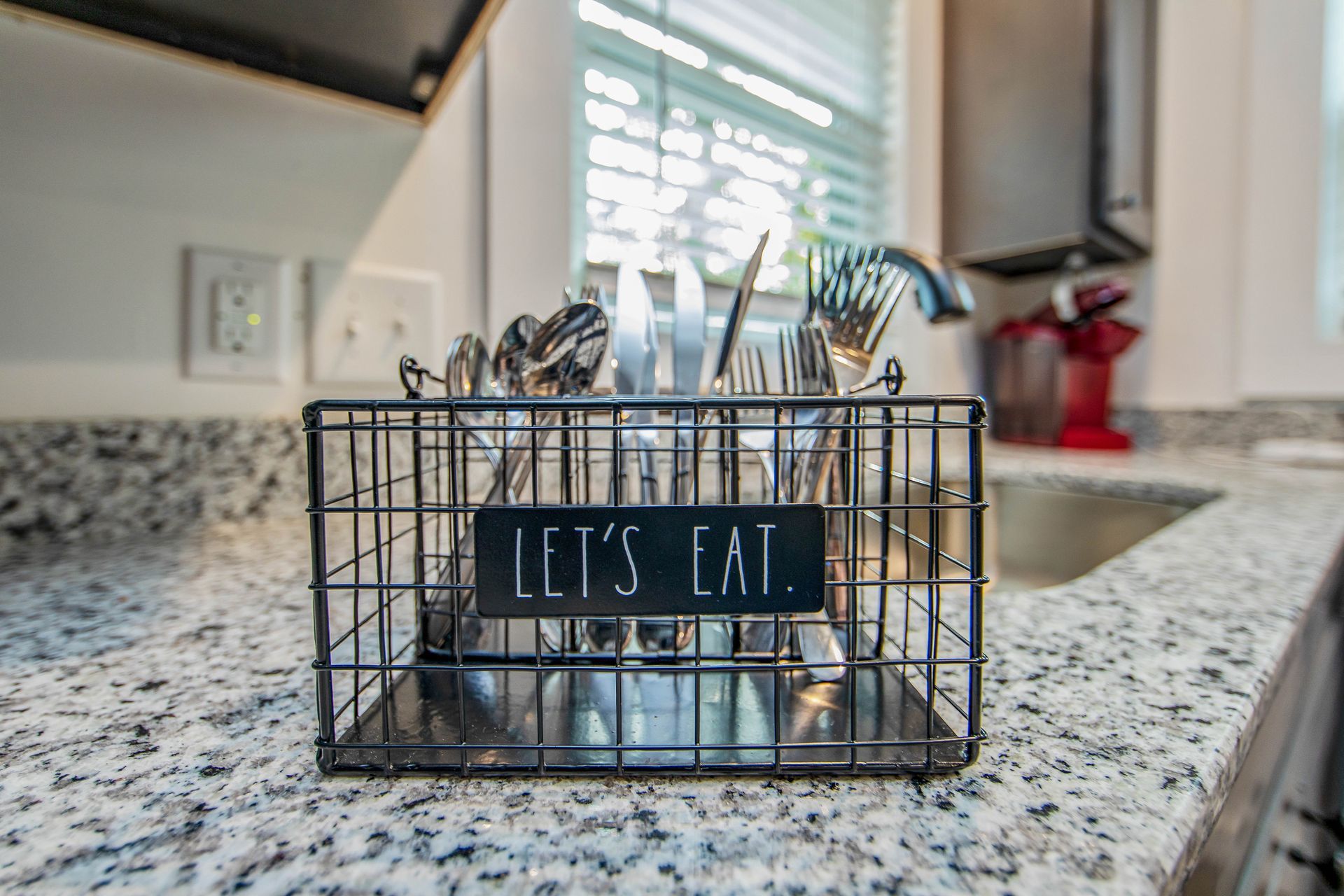 A kitchen counter with a utensil holder that says `` let 's eat ''.