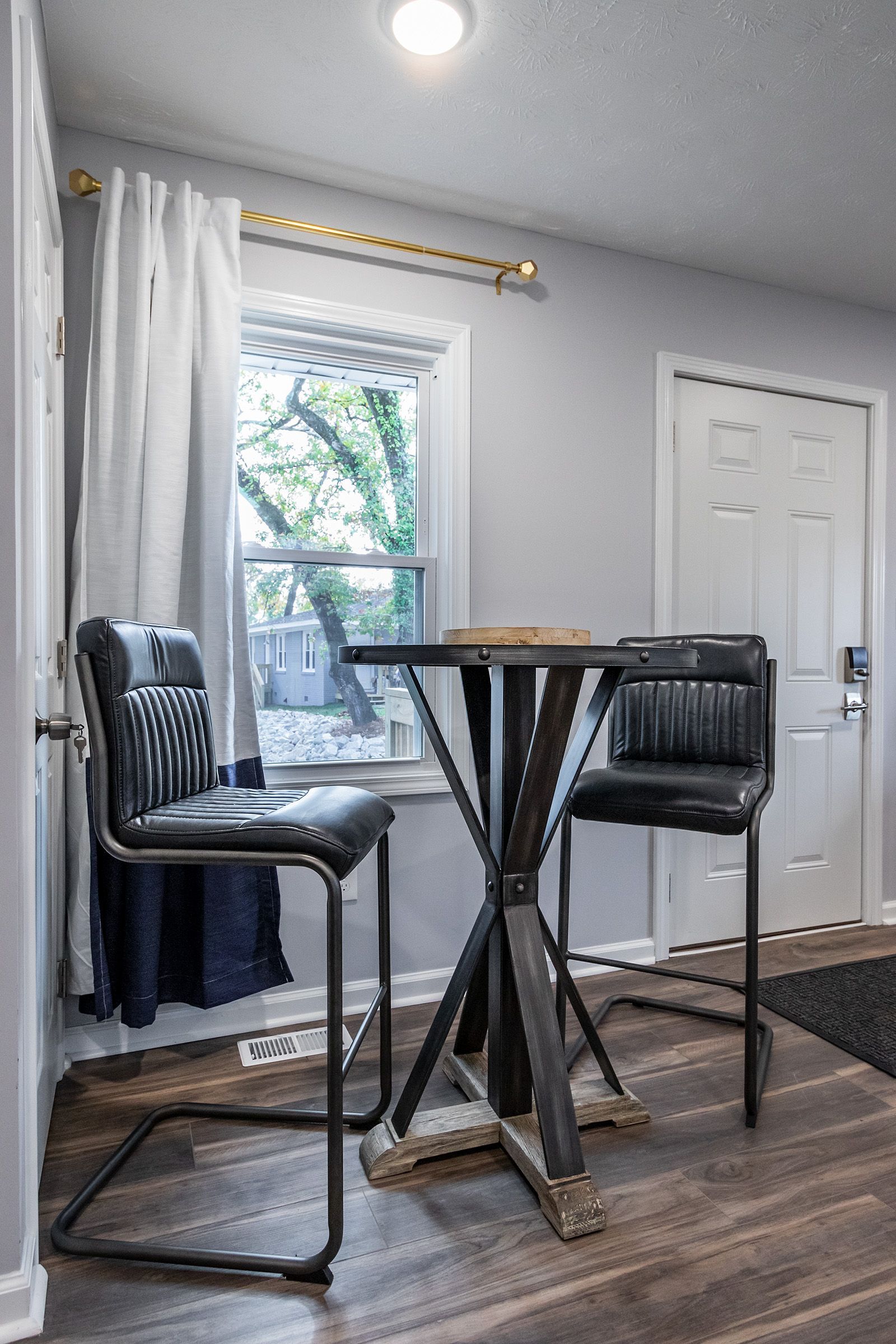 A dining room with a table and chairs in front of a window.
