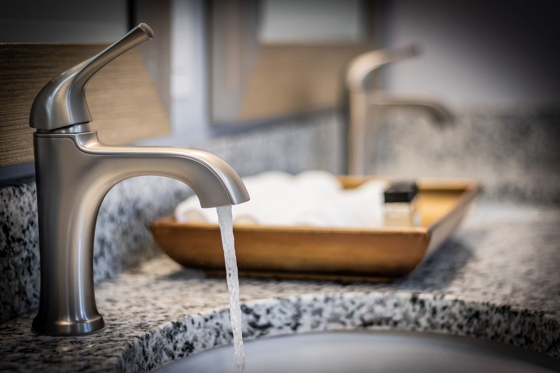 A bathroom sink with two faucets and water running out of it.
