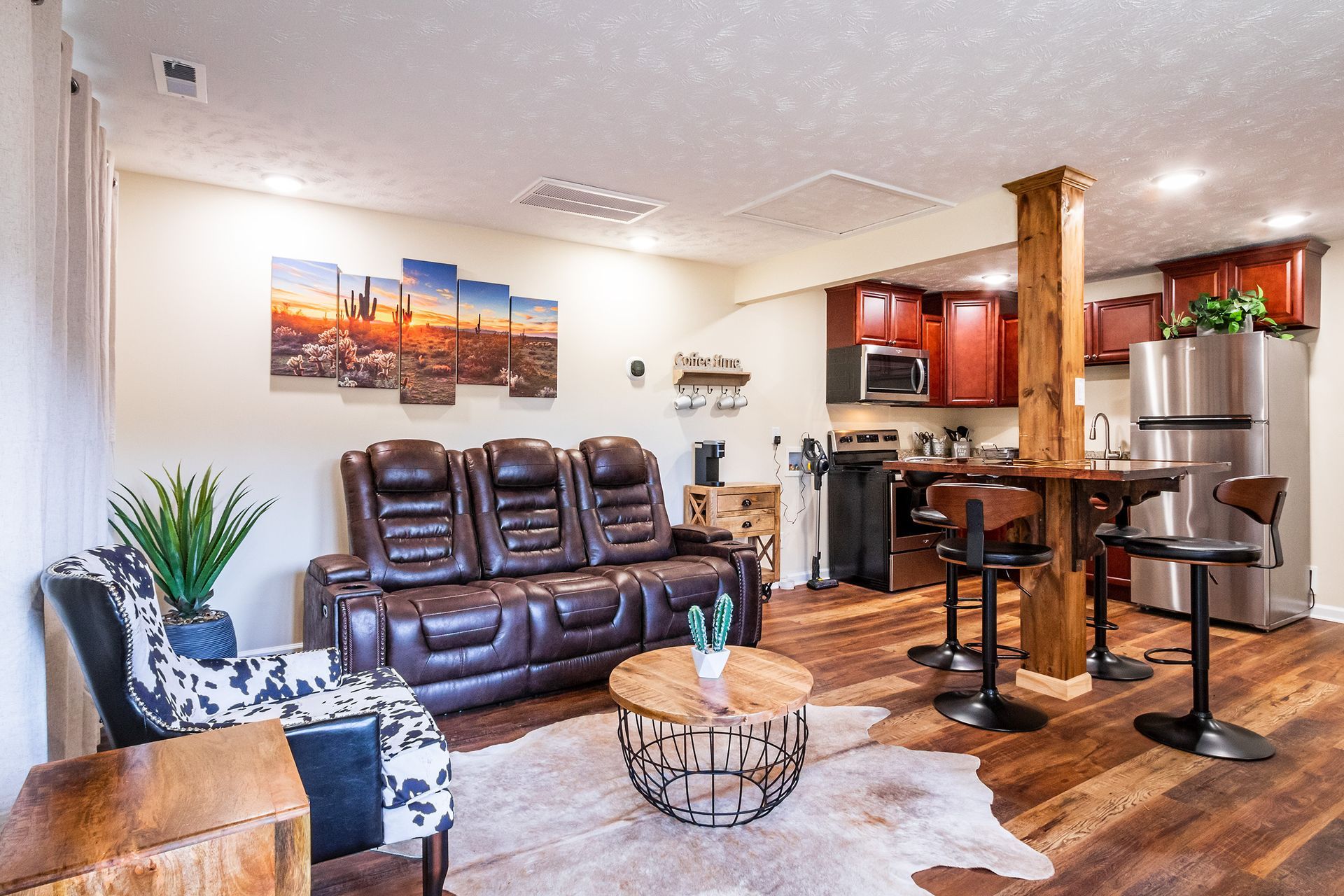 A living room with a couch , chair , coffee table , and kitchen.