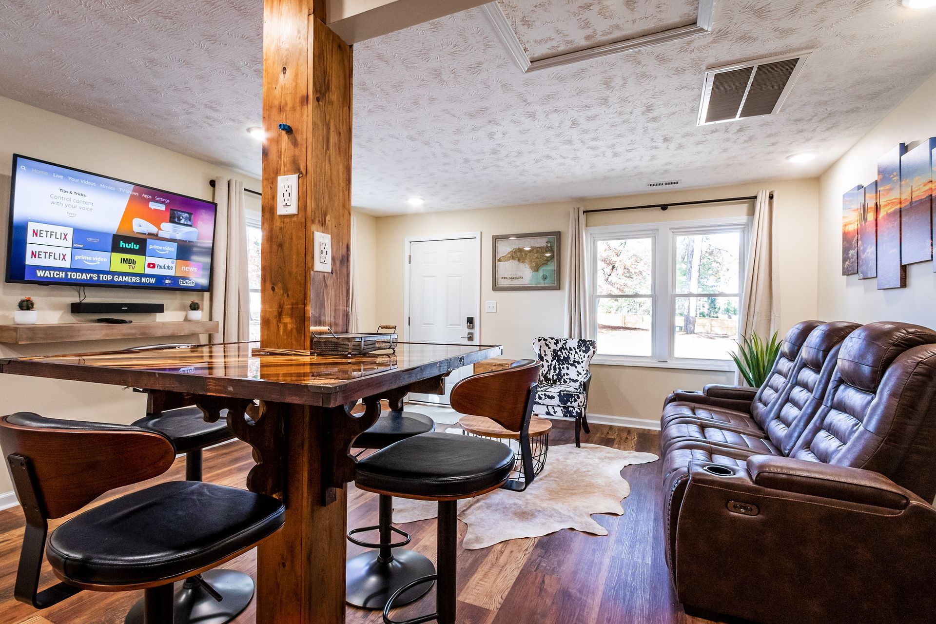 A living room with a couch , table , chairs and a flat screen tv.