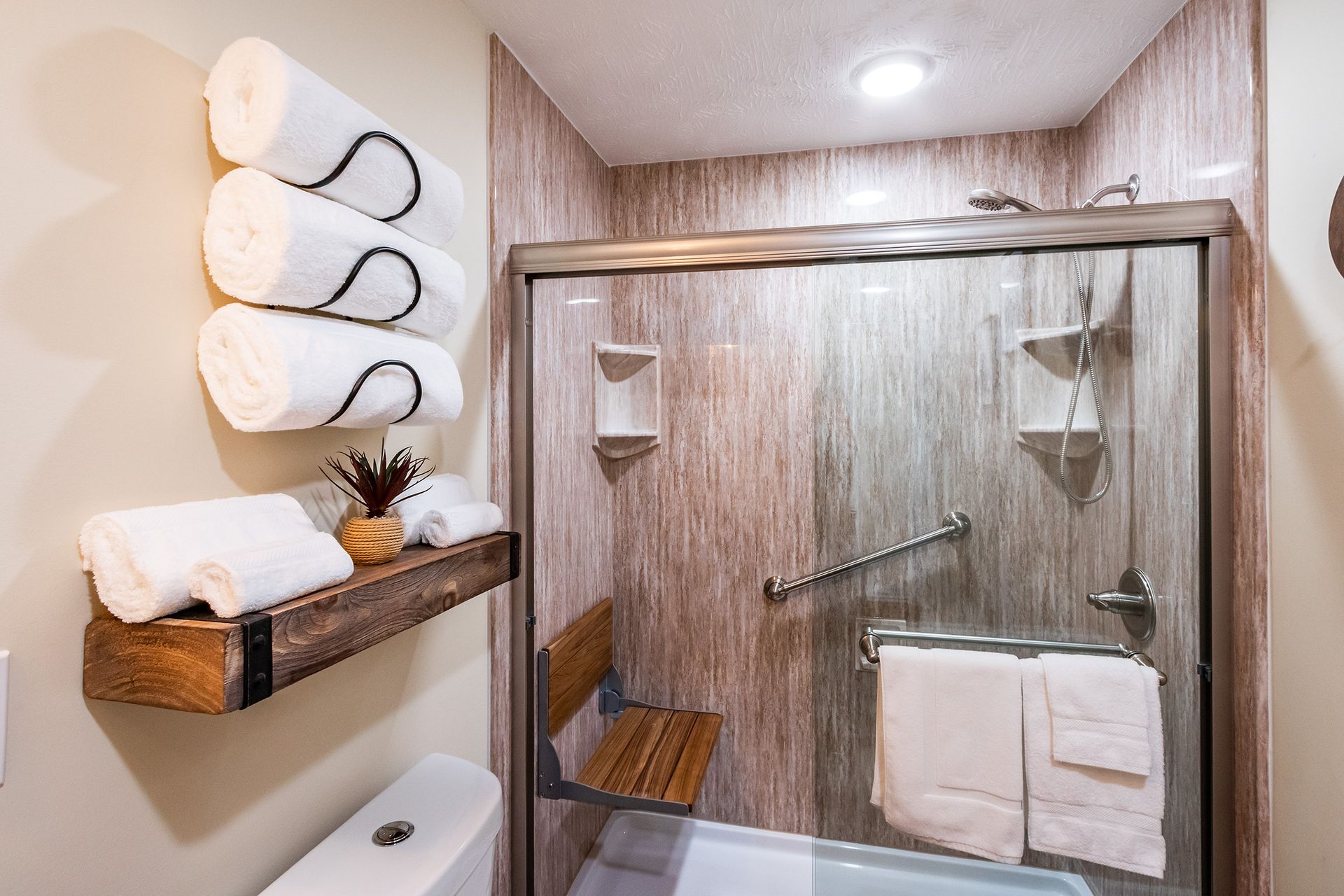 A bathroom with a tub , shower , toilet and towels.