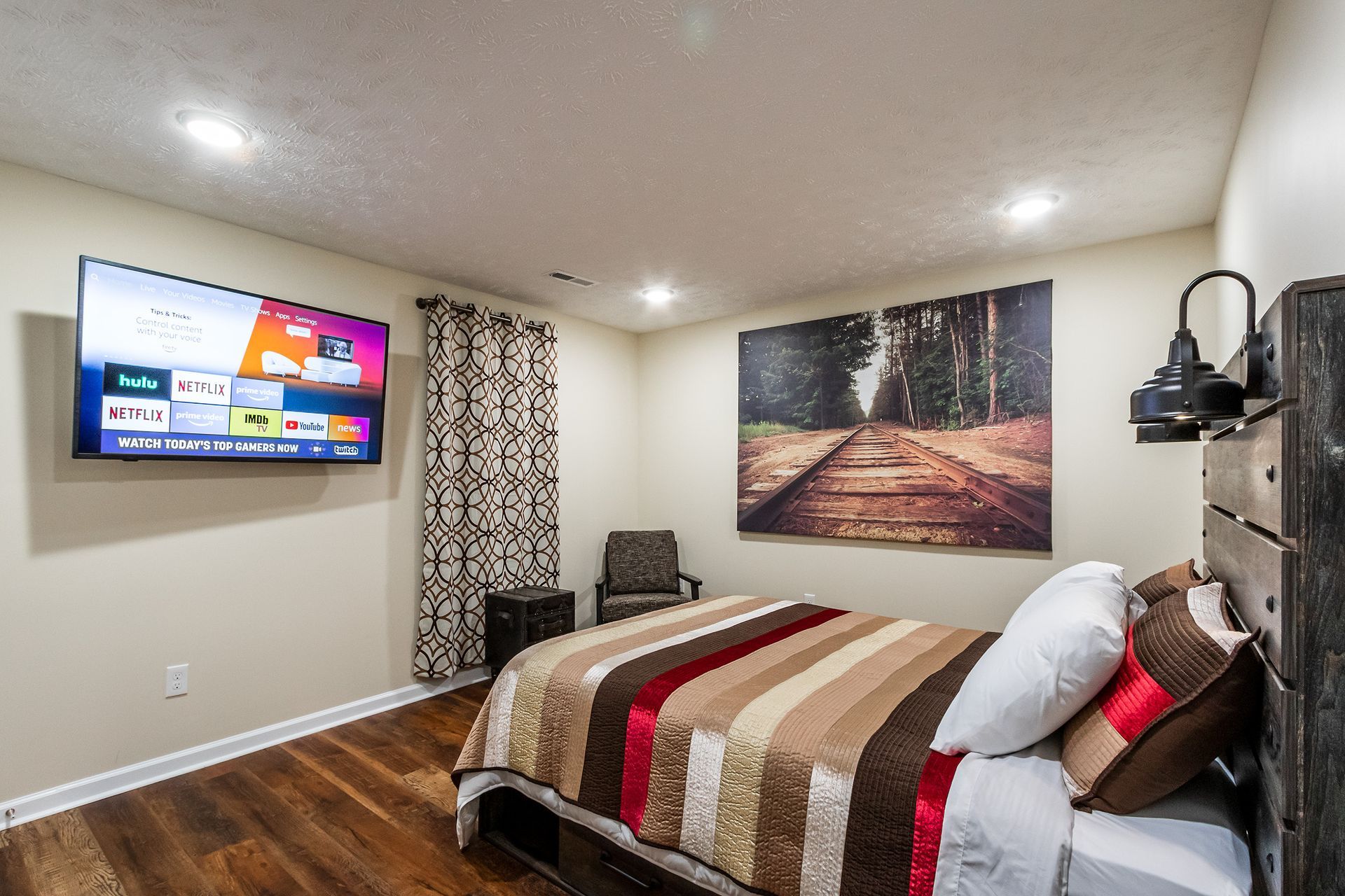 A bedroom with a bed and a flat screen tv on the wall.