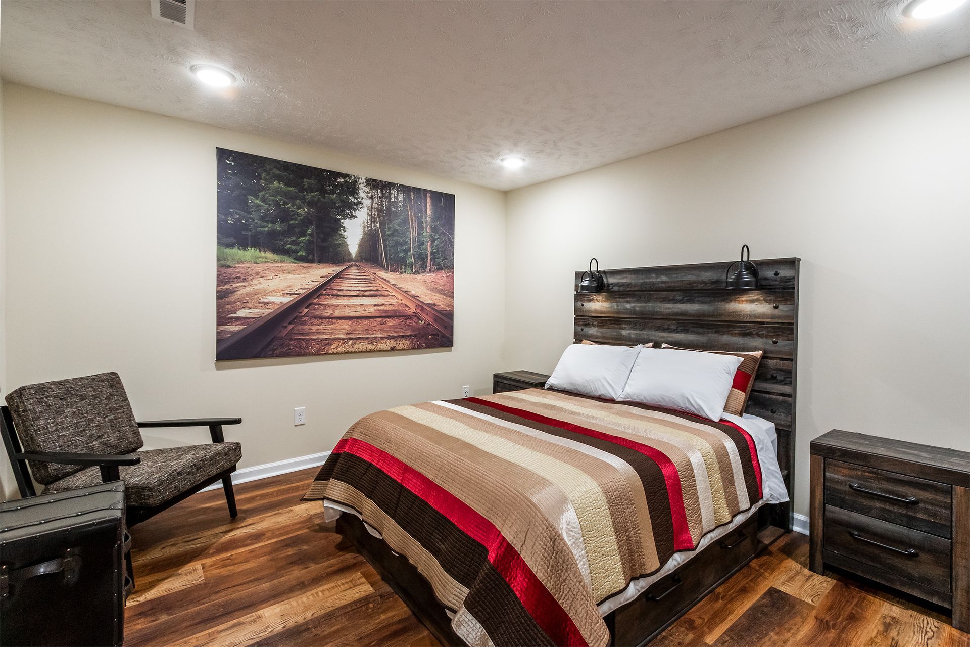 A bedroom with a bed , chair , nightstand and a painting on the wall.